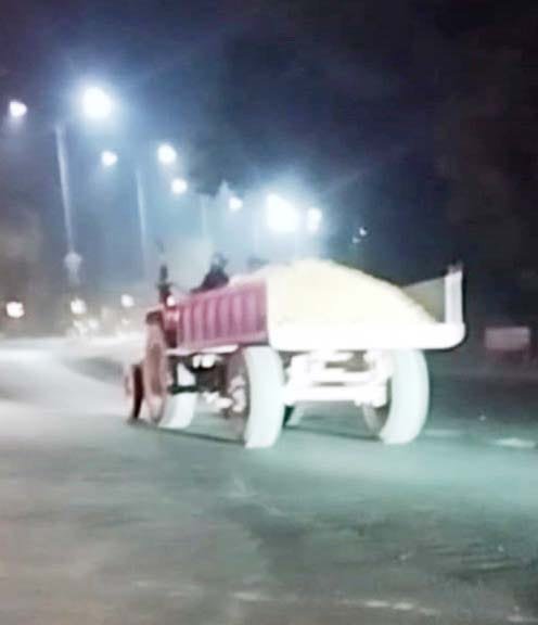 नदी के बीच रास्ता बना कर निकल रहे रेत और मिट्टी से लदे ट्रैक्टर