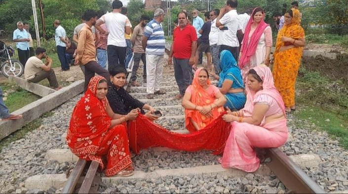रास्ता बंद होता देख महिलाओं ने रेलवे ट्रैक पर दिया धरना